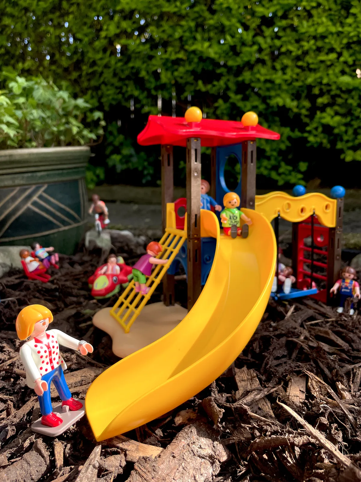 Playmobil play park toys and characters, Mum waiting for child on the slide while other children play.